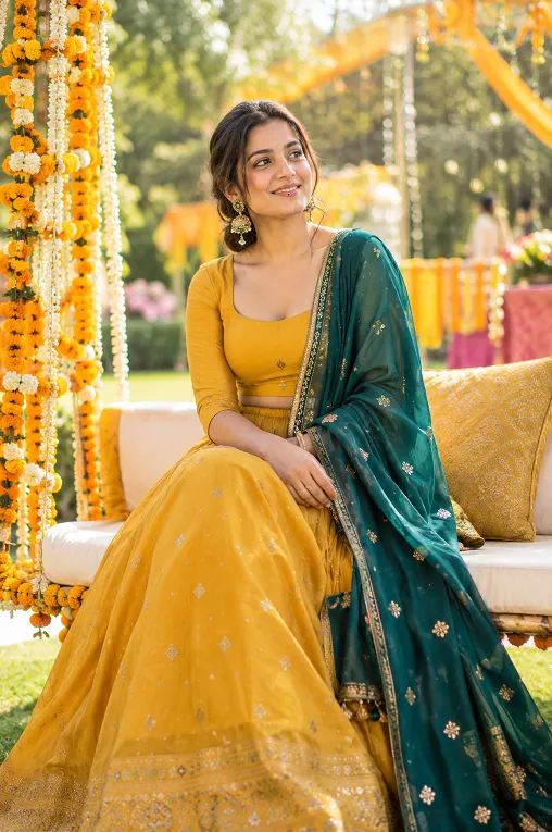 Guest in a mustard yellow lehenga at an outdoor daytime mehendi function