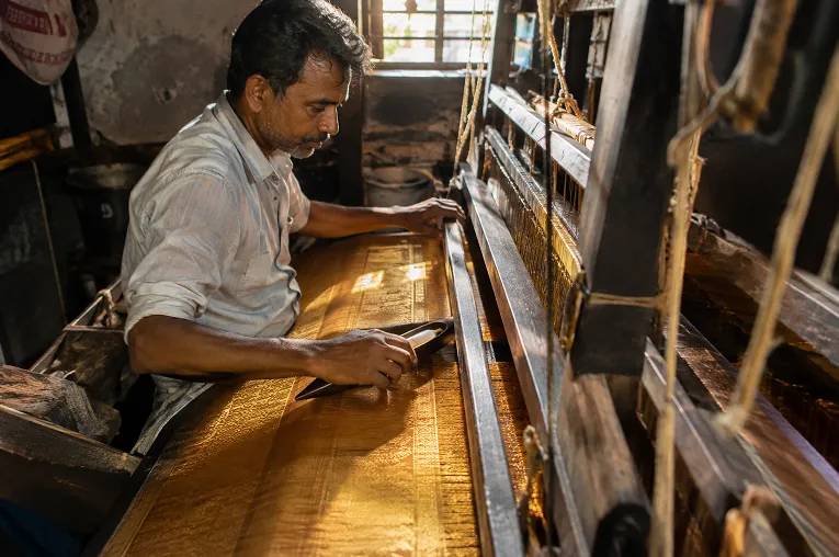 Weaver working on a traditional pit loom in Surat weaving a silk saree