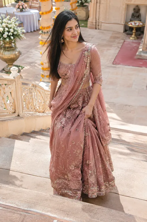 Woman walking in a lehenga up haveli steps while gathering the skirt at her hip