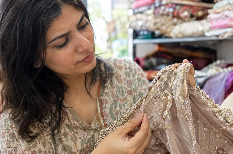 Woman turning a lehenga blouse inside out to check embroidery finishing and sequin stitching