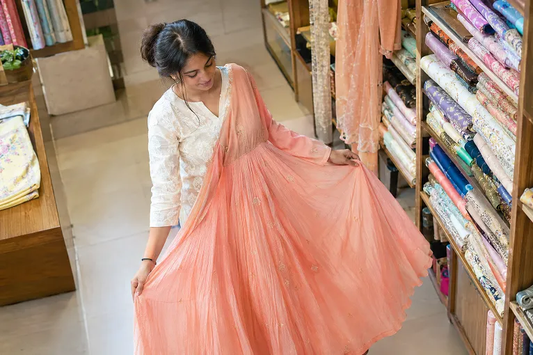 Woman checking the hem sweep of a georgette Anarkali in a bright Surat boutique