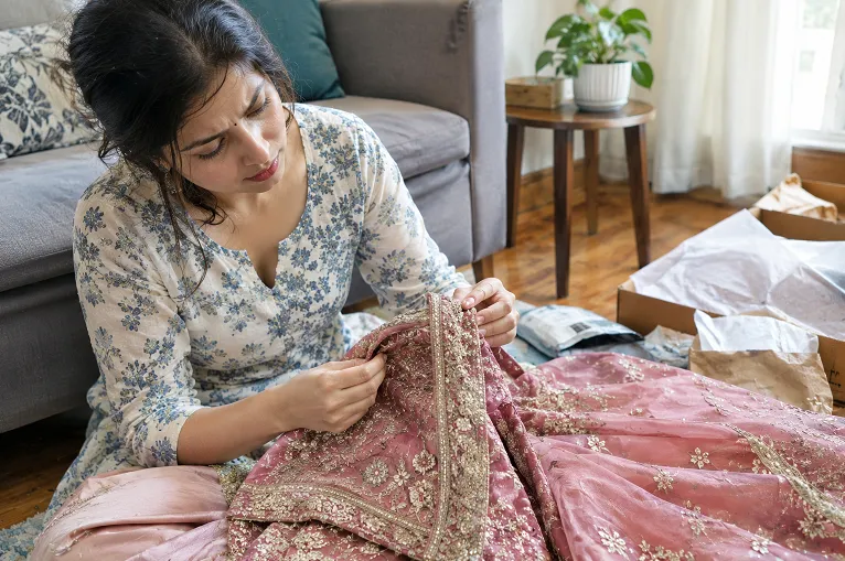 Checking a newly arrived lehenga for loose threads and finishing issues