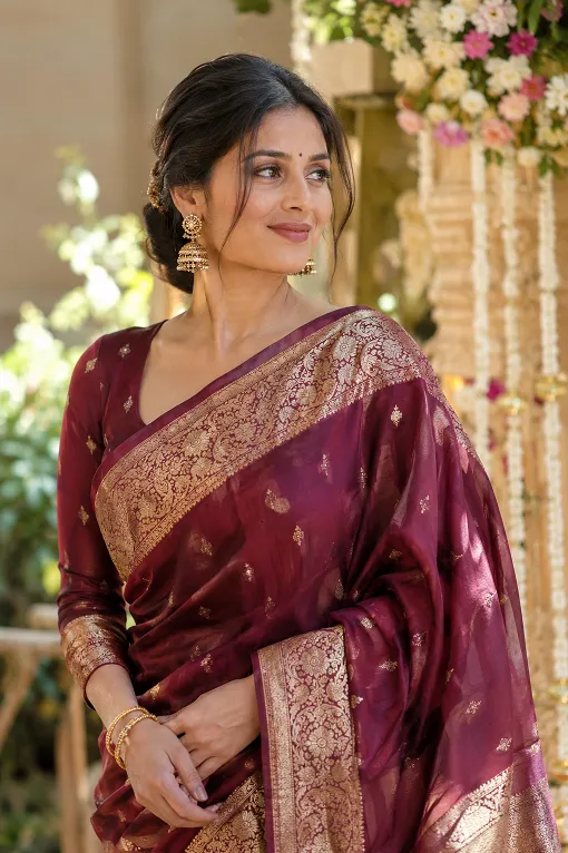 Woman in a maroon Banarasi silk saree at an evening wedding ceremony