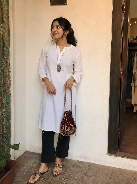 Young woman styling a plain white kurta with black jeans and statement accessories for a trendy college outfit