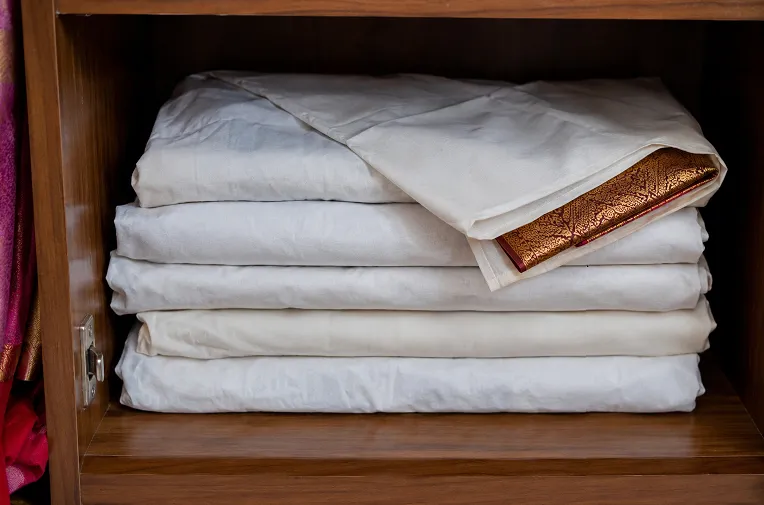 how to store silk sarees in a wardrobe: Silk sarees wrapped in cotton cloth and stored safely inside a wooden wardrobe