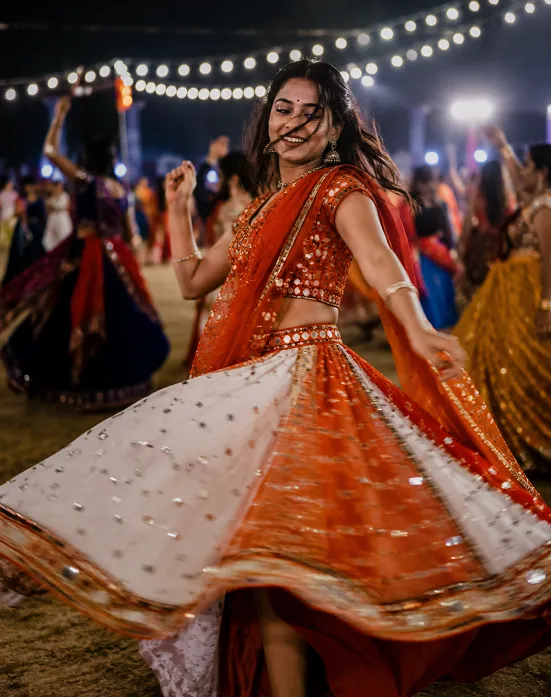 Woman dancing Garba in a flared chaniya choli showing fabric swirl in motion at night