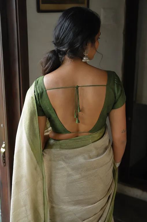 Indian woman with broad shoulders wearing a deep V back saree blouse with a thin string tie, showing a flattering blouse back design in natural daylight.
