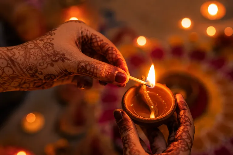 Close-up of hands lighting diya during Diwali evening celebration