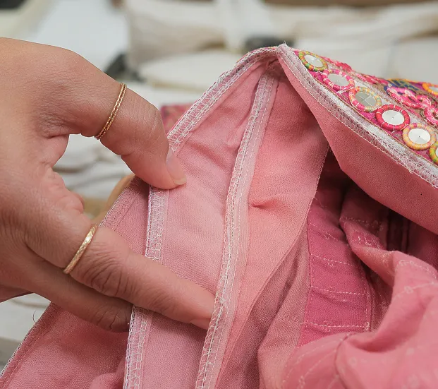 Close up of hand checking kali panel seam and mirror work stitching quality on a chaniya choli