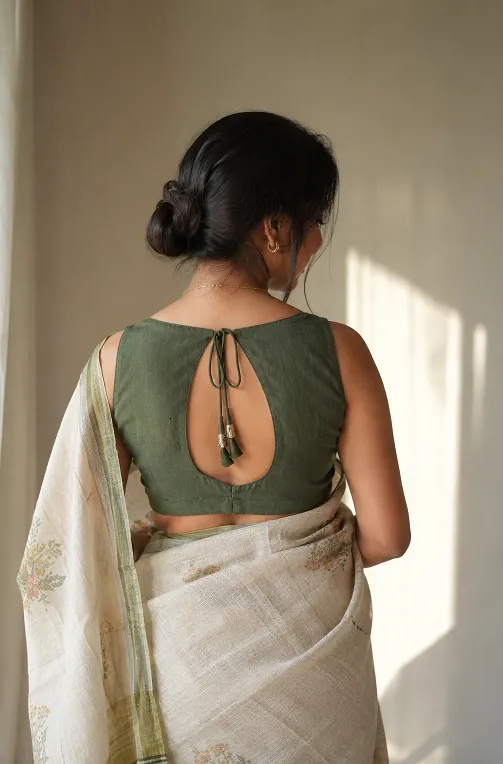 Petite Indian woman wearing a keyhole back saree blouse with a dori tie and tassels, showcasing an elegant back design in natural indoor light.