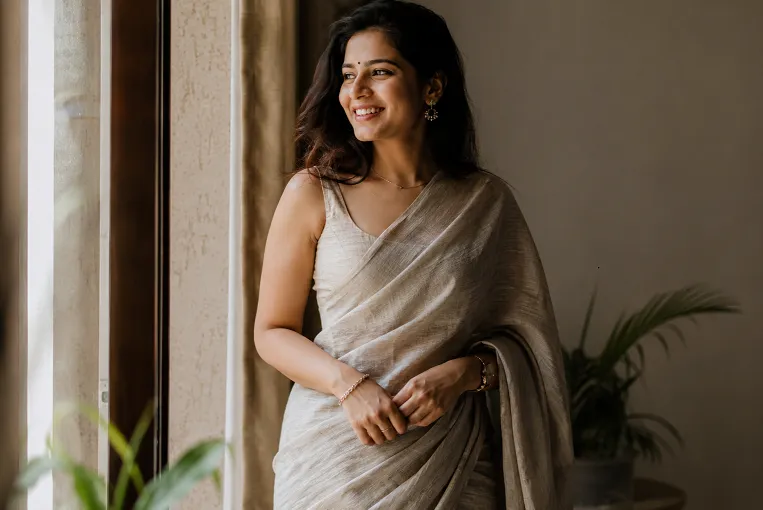 Woman wearing a linen saree draped in natural window light showing the fabric's natural fall