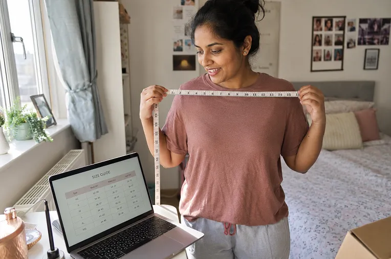 Woman measuring her shoulder width to order the correct Indian ethnic wear size in the UK