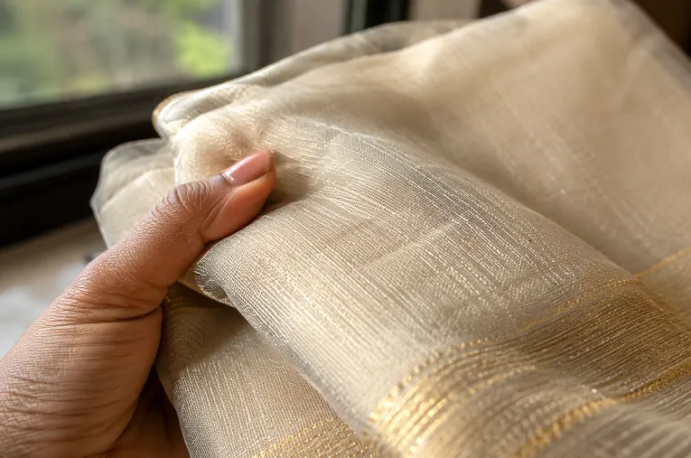 organza saree fabric texture held in hand near natural window light