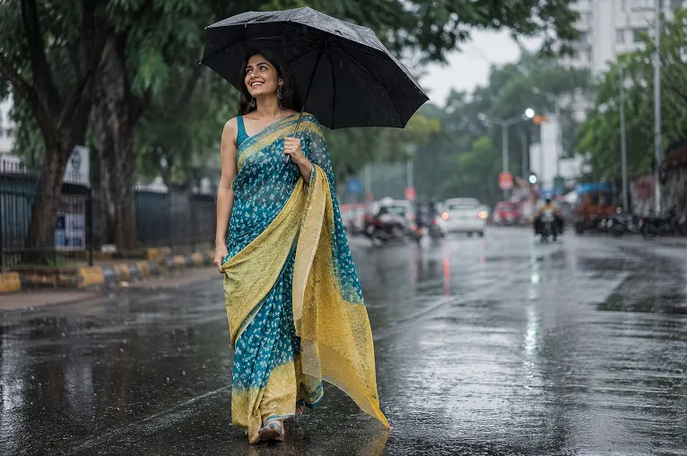 saree fabric for monsoon in printed georgette worn with an umbrella on a rainy street
