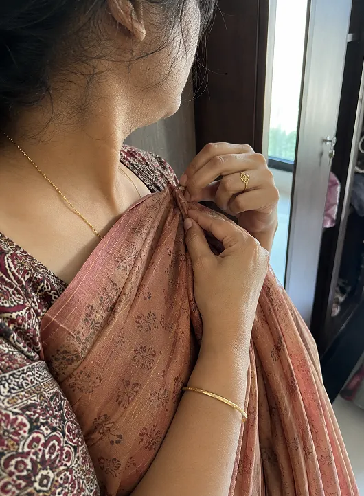Woman pinning saree pallu at the shoulder before leaving for the office