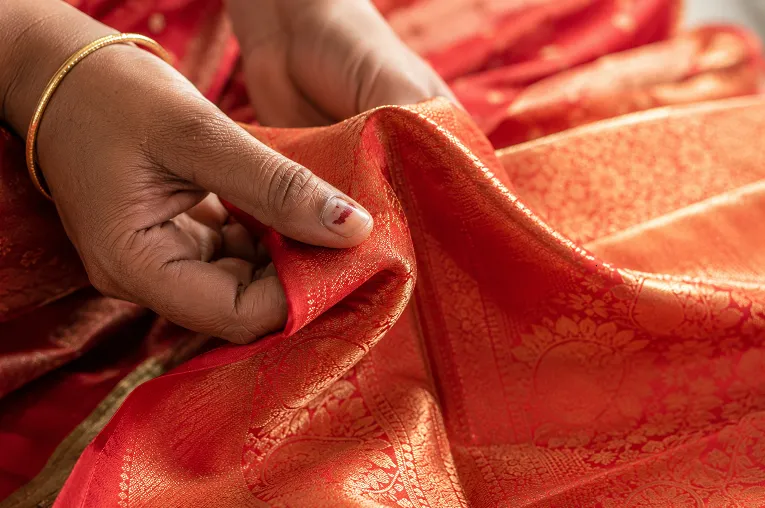 Close-up of silk saree fabric texture and drape showing genuine weight against fingers