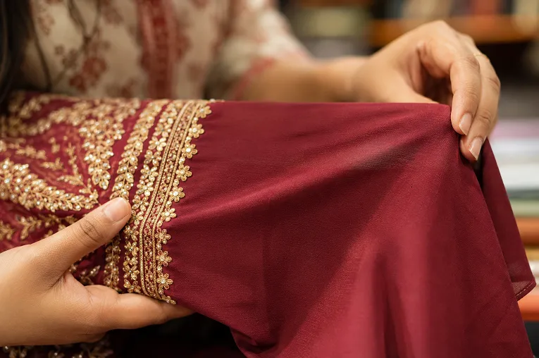 hands checking fabric stretch on an embroidered ethnic blouse before buying