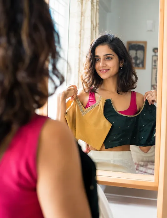Indian woman choosing a flattering neckline for face shape in front of a mirror