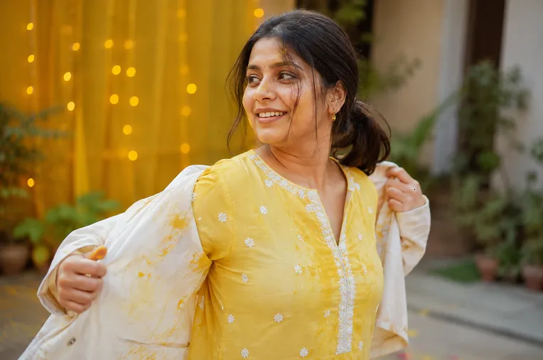 woman removing outer jacket layer after haldi ceremony turmeric application