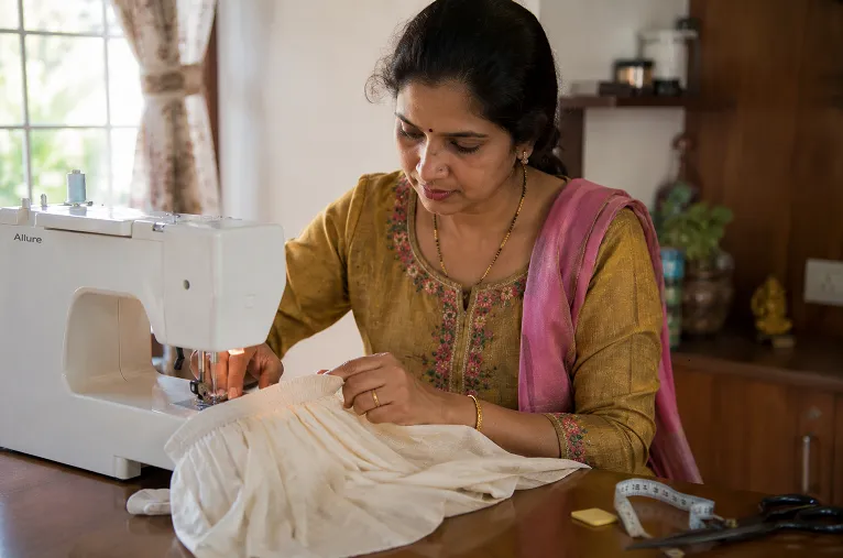 tailor stitching elastic waistband onto a pleated ready to wear saree